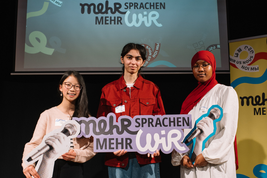 Drei Teilnehmer:innen von Mehr Sprachen - mehr WIR auf der Bühne.