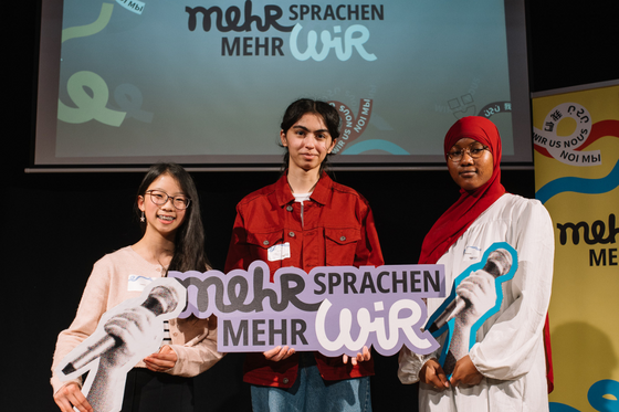Drei Teilnehmer:innen von Mehr Sprachen - mehr WIR auf der Bühne.