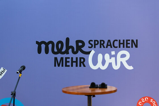 Mikrofone vor "Mehr Sprachen - mehr WIR"-Leinwand